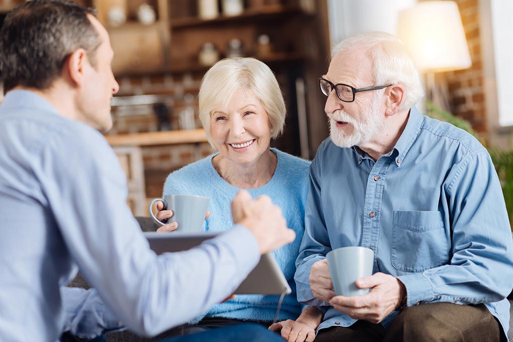 Ein Seniorenehepaar bekommt von einem Mann Dinge auf einem Tablet gezeigt
