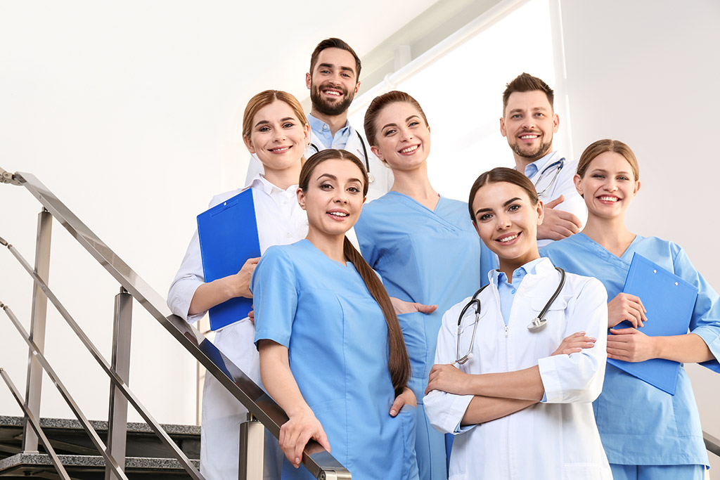 Gruppe von Ärztinnen und Ärzten mit Pflegepersonal auf einer Treppe