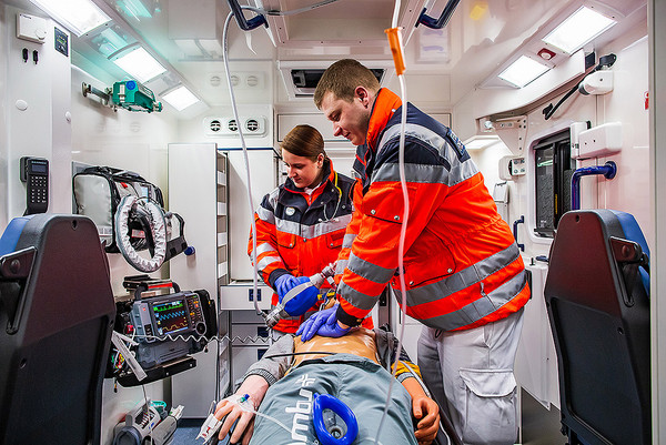 Zwei Rettungssanitäter trainieren in einem Rettungswagen an einer Puppe