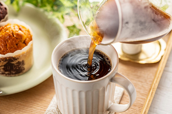 Auf einem Kaffeetisch wird eine Tasse mit Kaffee gefüllt