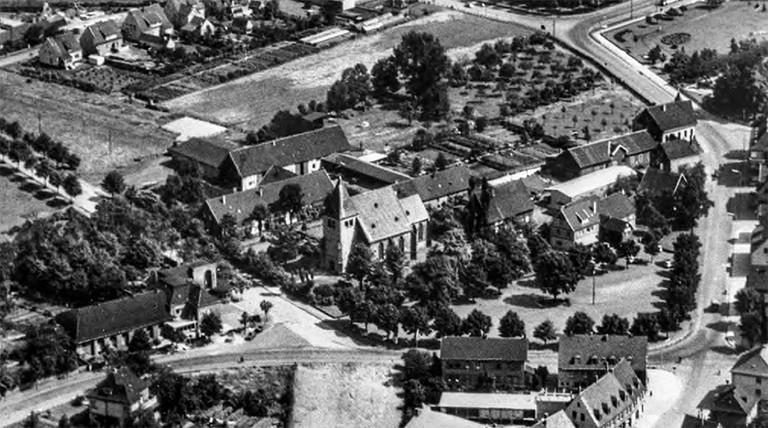 Herringer Markt mit der St. Viktor Kirche im Zentrum, gesehen von Südwesten. Luftaufnahme aus den 1950er-Jahren