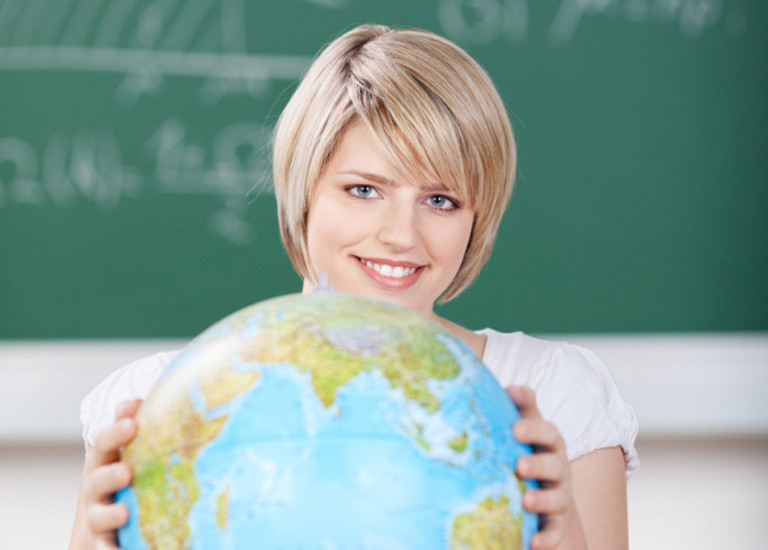 Studentin mit Globus vor einer Tafel