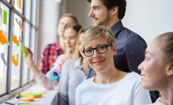 Eine lächelnde Frau arbeitet im Team in einem Workshop