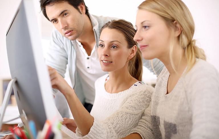 Eine Frau erklärt einer anderen Frau etwas an einem Computermonitor