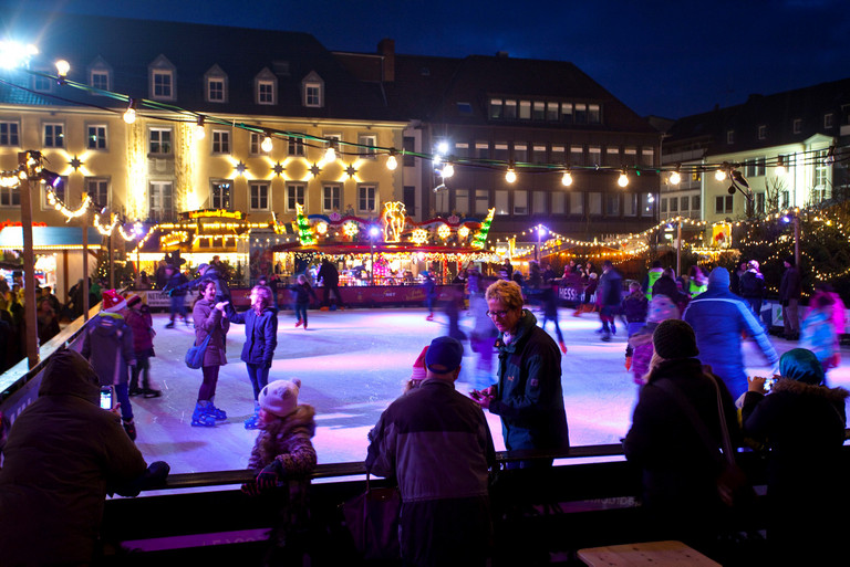 Eisläufer auf der Eisbahn im Weihnachtsmarkt-Dorf