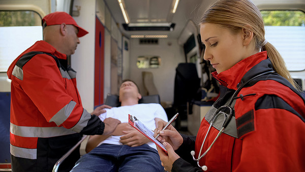 Zwei Rettungssanitäter betreuen eine kranke Frau