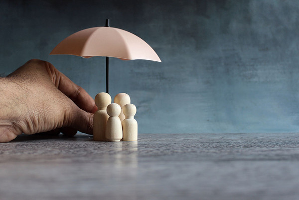 Hand hält Regenschirm mit Holzpuppen darunter