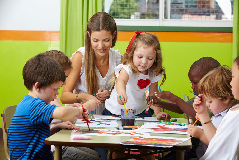 eine Erzieherin malt mit Kindern