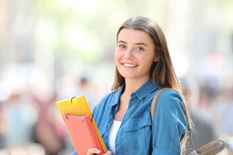 Eine junge Studentin mit Arbeitsmappen im Arm