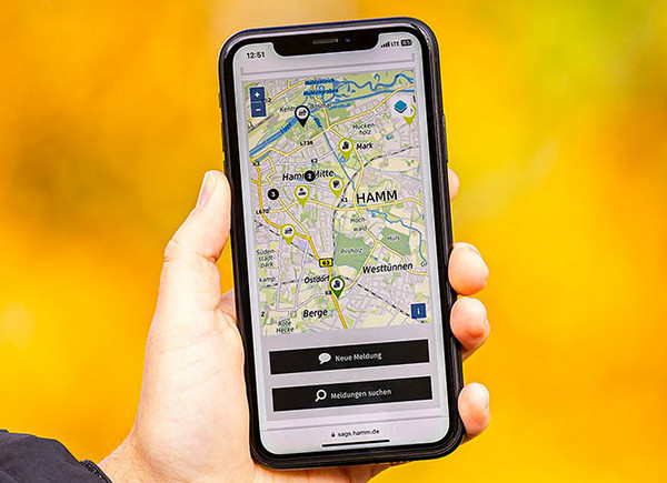 Eine Hand hält ein Handy mit dem Mängelmelder der Stadt Hamm
