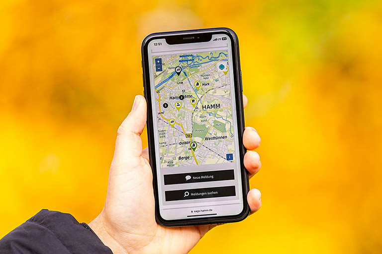 Eine Hand hält ein Handy mit dem Mängelmelder der Stadt Hamm