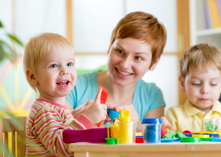 Eine Frau/Erzieherin spielt mit Kindern