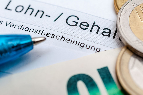 Geld und Kugelschreiber auf einer Verdienstbescheinigung