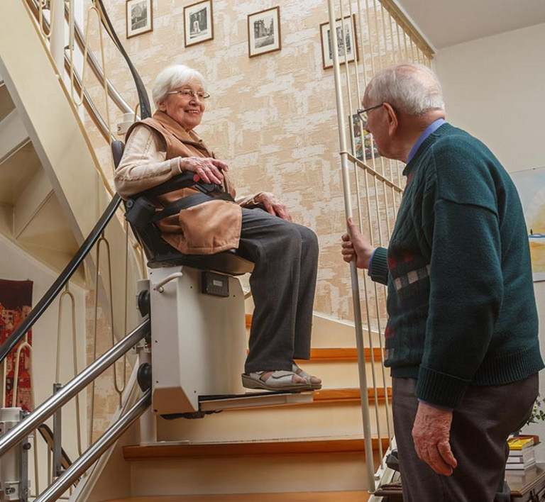 Ein älteres Ehepaar an einem Treppenlift