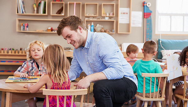 Ein Erzieher spielt mit Kindern in der Kita 