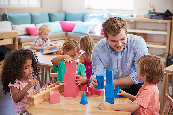 Ein Erzieher spielt mit Kindern in der Kita  