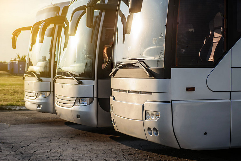 Drei silberne Busse, bei Sonnenuntergang auf dem Parkplatz