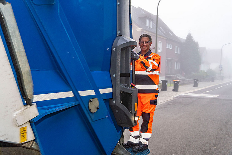 OB Marc Herter fährt auf einem Müllwagen mit