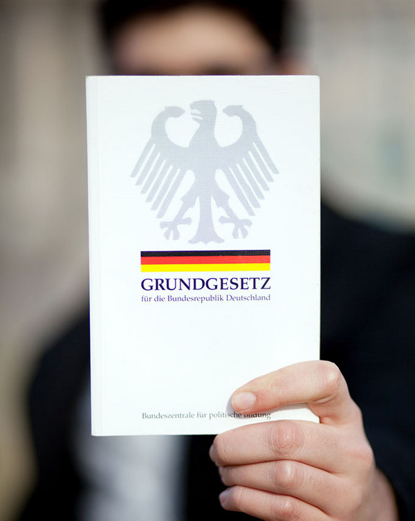 männliche Hand zeigt das Grundgesetz