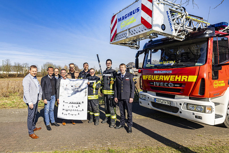 Der OB sowie Mitarbeiter der Verwaltung und der Feuerwehr stehen an einem Feuerwehrauto