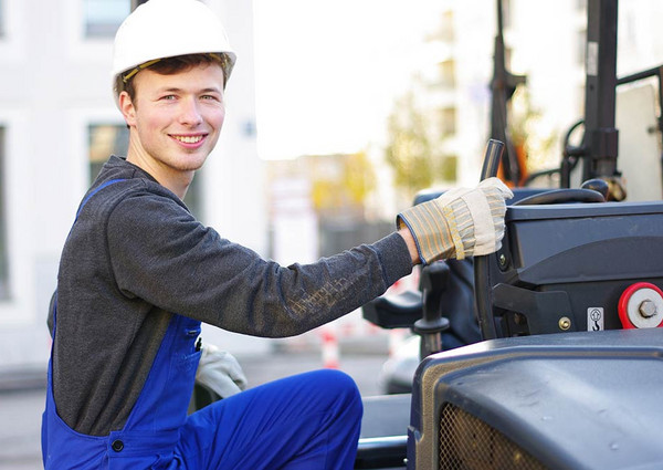 Ein freundlich lächelnder Bauarbeiter besteigt eine Baumaschine