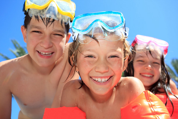 drei Kinder mit Taucherbrillen und Schwimmflügeln