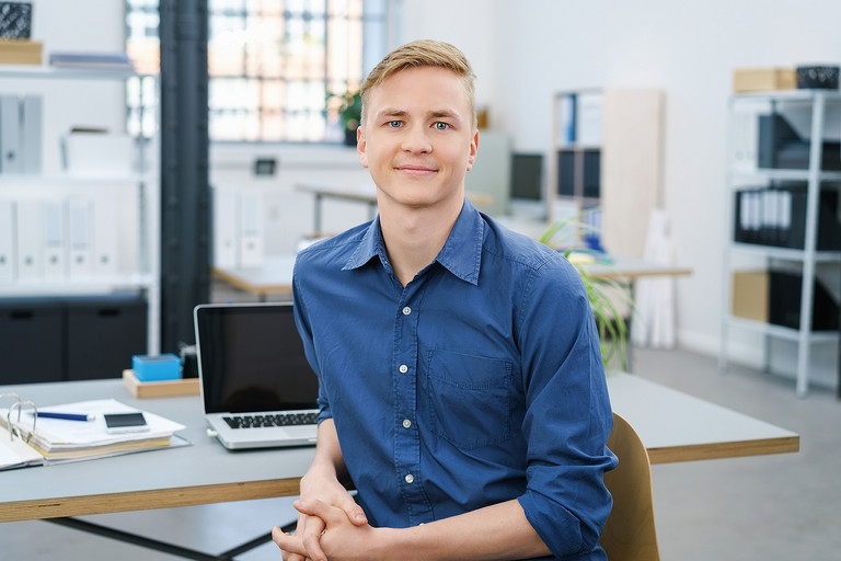 Ein junger Mann sitzt vor seinem Schreibtisch im Büro