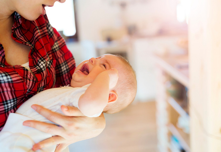 schreiendes Baby auf dem Arm seiner Mutter