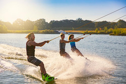 Drei junge Leute beim Wakeboarden