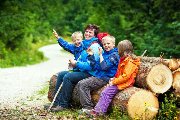 Familie bei kleiner Pause auf Baumstämmen im Wald