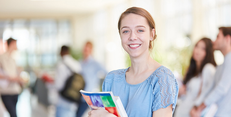 Eine junge Frau mit Büchern im Arm