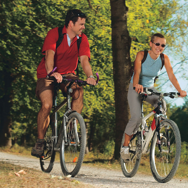 Paar fährt mit Mountainbikes auf Feldweg 