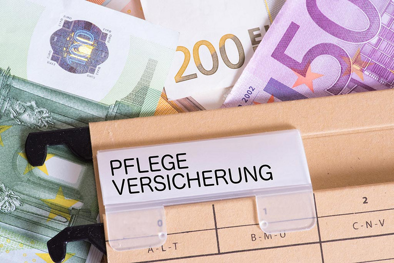 Eine Akte mit der Bezeichnung ''Pflegeversicherung'' liegt auf verschiedenen Geldscheinen