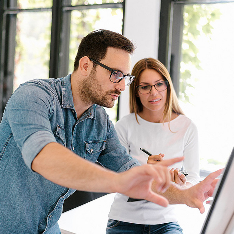 Ein Mann und eine Frau stehen diskutierend vor einem Flipchart