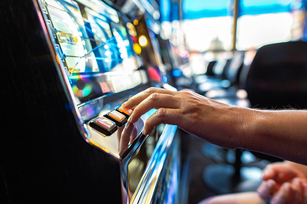 Ein Finger drückt auf einen Knopf an einem Geldspielautomaten